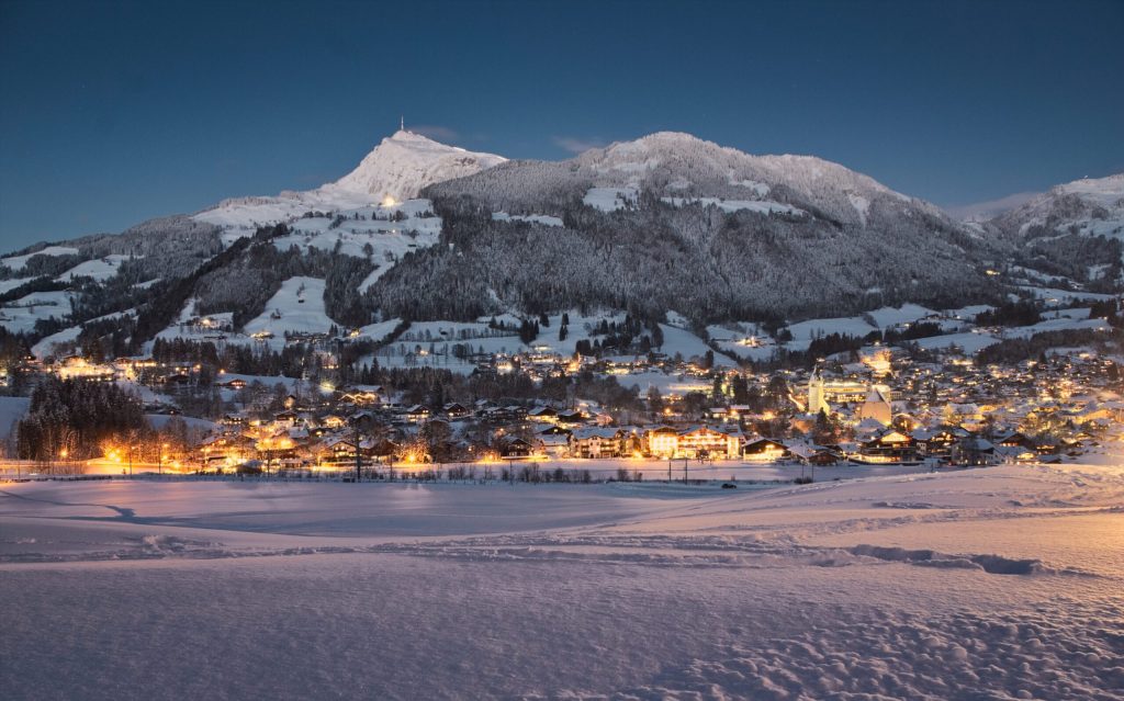 Escort Kitzbühel - Malerische Winterlandschaft bei Nacht mit kleiner Stadt