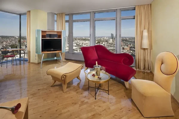 Stilvoll eingerichtete Suite mit rotem Designersofa und Panoramablick über Frankfurt – luxuriöses Ambiente für Escort Frankfurt Erlebnisse