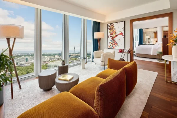 Elegante Hotel-Suite mit bodentiefen Fenstern, gemütlichem Sofa und Weitblick über Frankfurt – exklusives Umfeld für Escort Frankfurt Treffen.